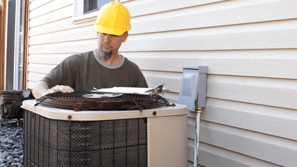 Technician inspecting an outdoor air-conditioning coil