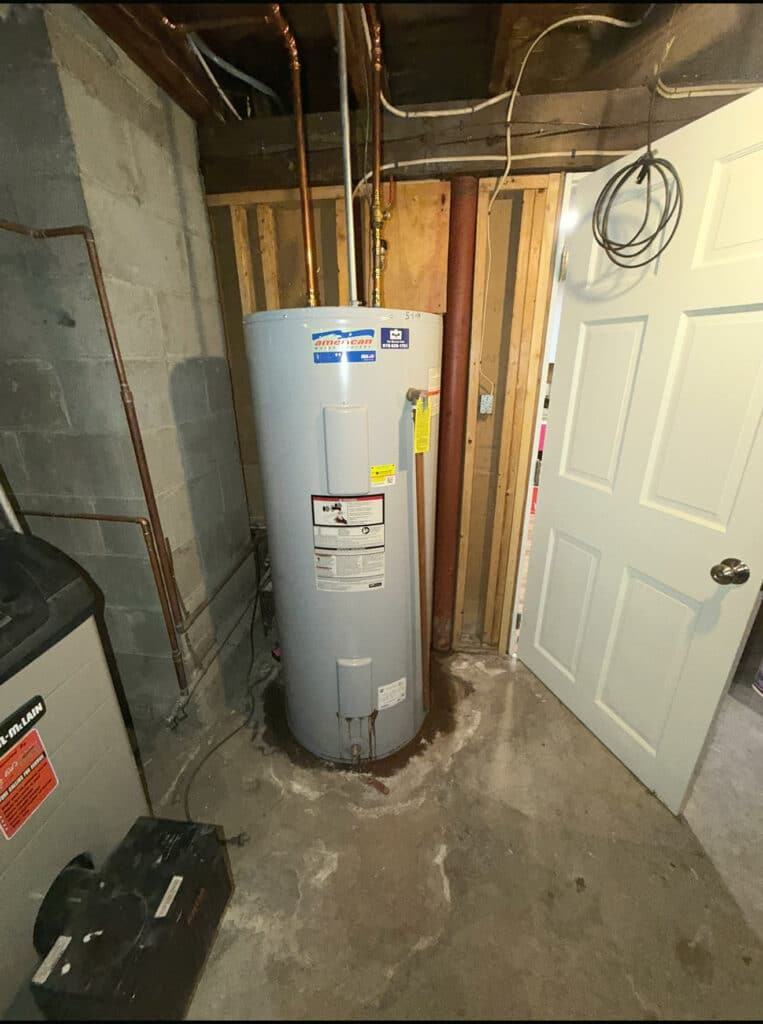 Original standard electric water heater in the basement before replacement